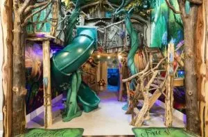A fantasy forest playroom has climbing frames, slides and hidden doors