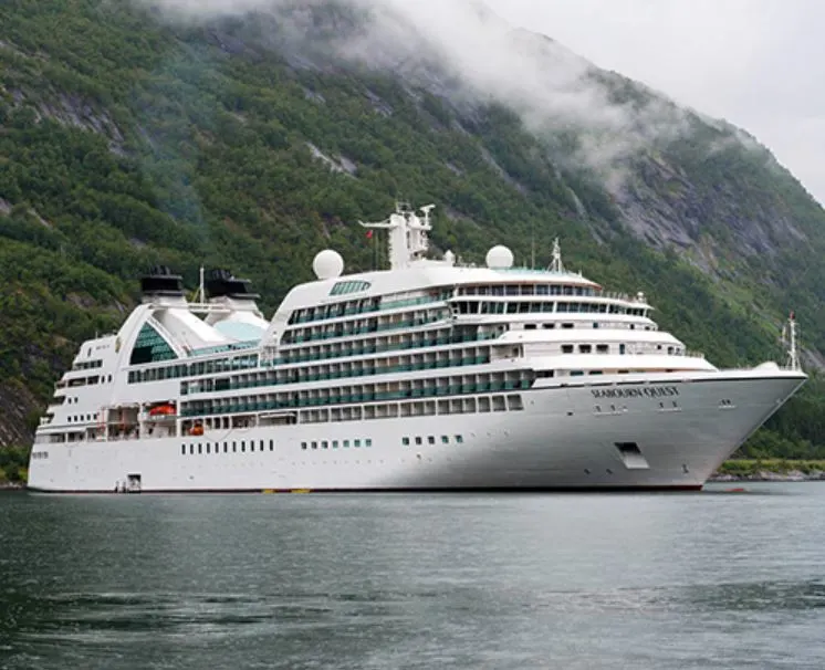 seabourn cruise ship docked by green mountain