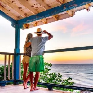 Young couple on a tropical island, standing on the terrace of an old colonial house, looking towards the sea. Havana, Cuba