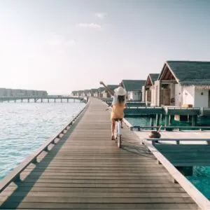 Young Woman Riding Bycicle In A Wooden Pier In The Maldives