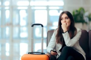 Sad Melancholic Woman At Airport With Suitcase After A Potential Flight Cancelation Or Flight Disruption