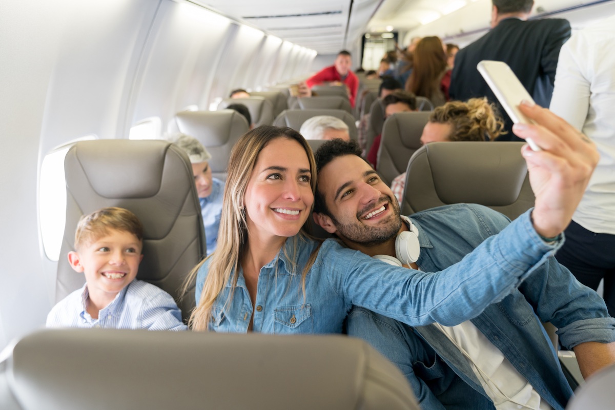 Happy family traveling by plane and taking a selfie - Travel Off Path