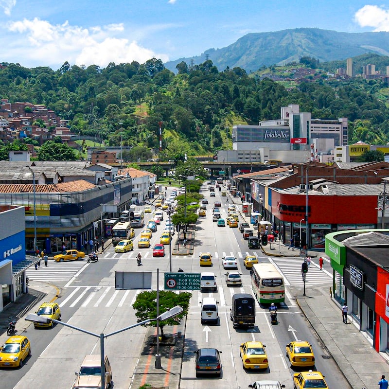 aerial view of Medellin busy street during the day, mountains in background. Medellin is one of the cheapest South American cities to fly from the U.S.
