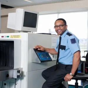 Smiling Male Airport Security Staff Carrying Out His Duty At An International Airport