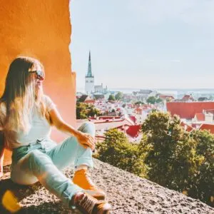 Woman sightseeing Tallinn city landmarks vacations in Estonia travel lifestyle girl tourist relaxing at viewpoint Old Town aerial view architecture