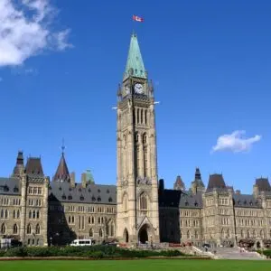 Canadian Flag Flying High On Top Of The Parliament Building In Ottawa, Capital Of Canada