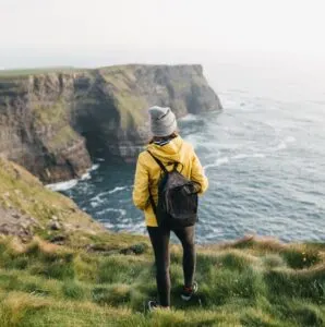 Cliffs of Moher Backpacker Stands on Edge of Cliff
