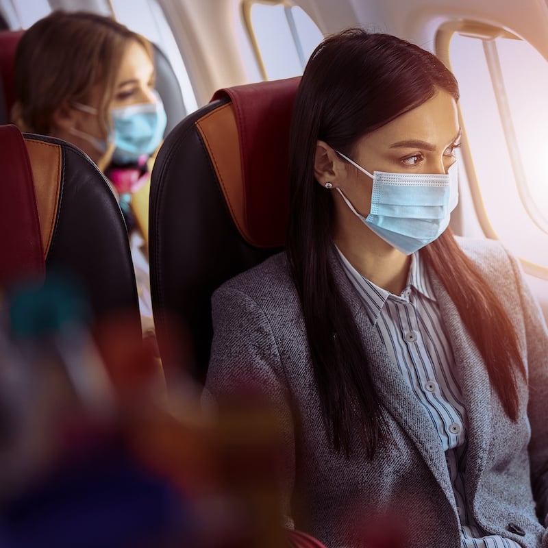 Kvinna som bär mask på flygplan