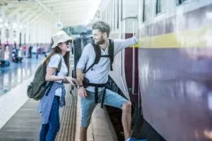 Couple Of Young Happy Travelers Getting On A Train, Train Travel Concept