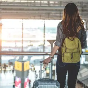 Woman in airport facing away from camera with luggage