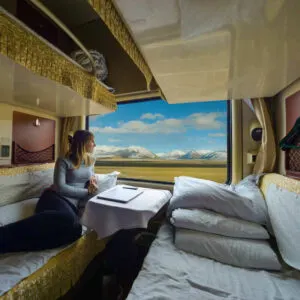 Young Woman Staring Out The Window As She Takes A Scenic Train Journey With Snowy Mountains For A View