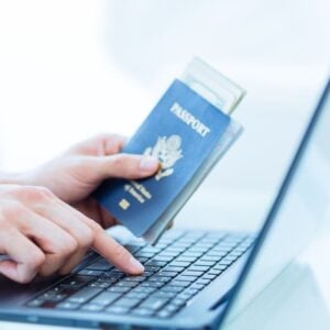 Man using laptop with passport in his hand