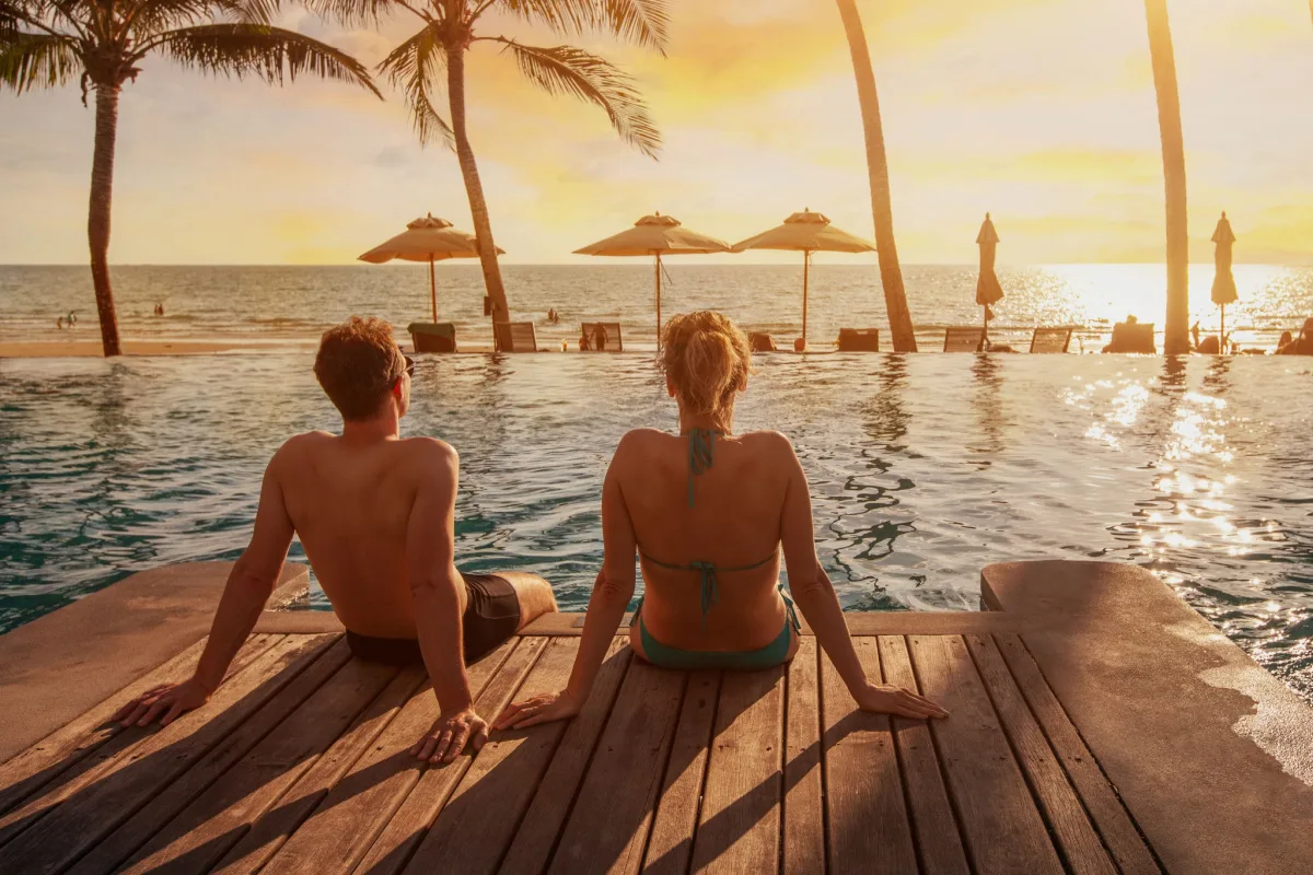 A couple watches the sunset by a pool