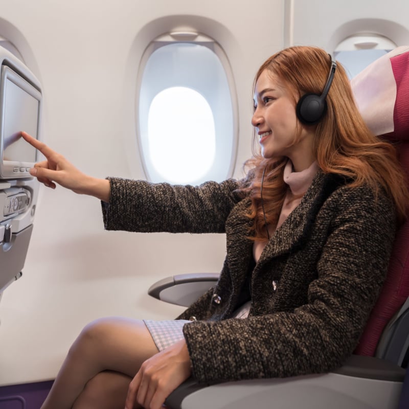 woman touching LCD entertainment screen on the airplane