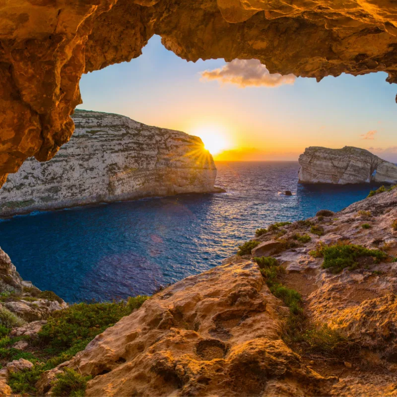 the sun sets behind rocks in picturesque Gozo