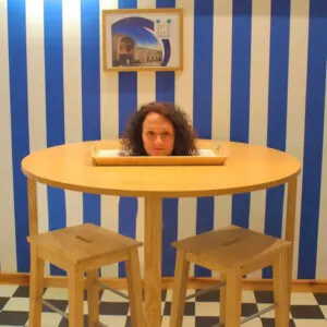 an optical illusion makes it appear as if a woman's head is on a dinner plate