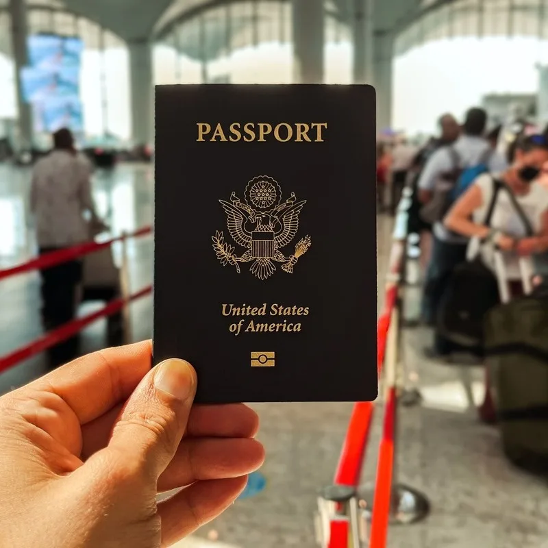 American Citizen Holding Up A U.S. Passport, American Passport As They Wait In A Queue At The Airport