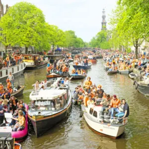 Amsterdam canals full of boats and people in orange during the celebration of kings day
