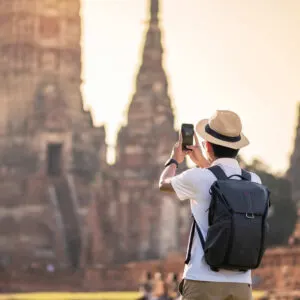 Backpacker Taking A Picture Of A Buddhist Temple In Thailand, Southeast Asia