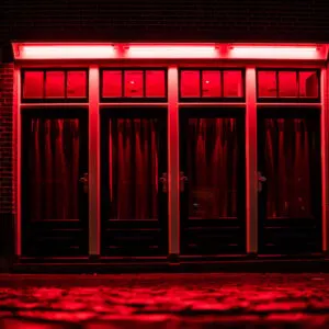 Red Light District in Amsterdam. Red boxes with curtains and rainy Cobbles on the street