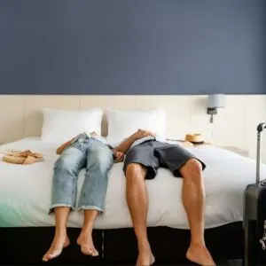 Travelers laying on hotel bed after arrival suffering from jet lag