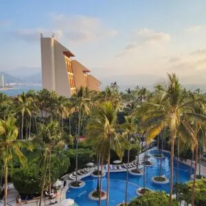 View off the balcony of westin, pools below with ocean and mountains in the distance