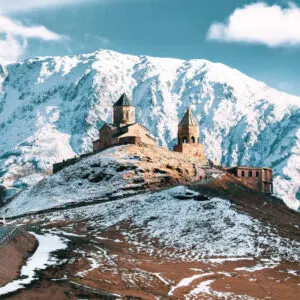 Gergeti Orthodox Church Set Against Snowy Peaks In Stepantsminda, An Alpine Town In The Country Of Georgia, Located In The Caucasus, A Region Between Eastern Europe And Western Asia