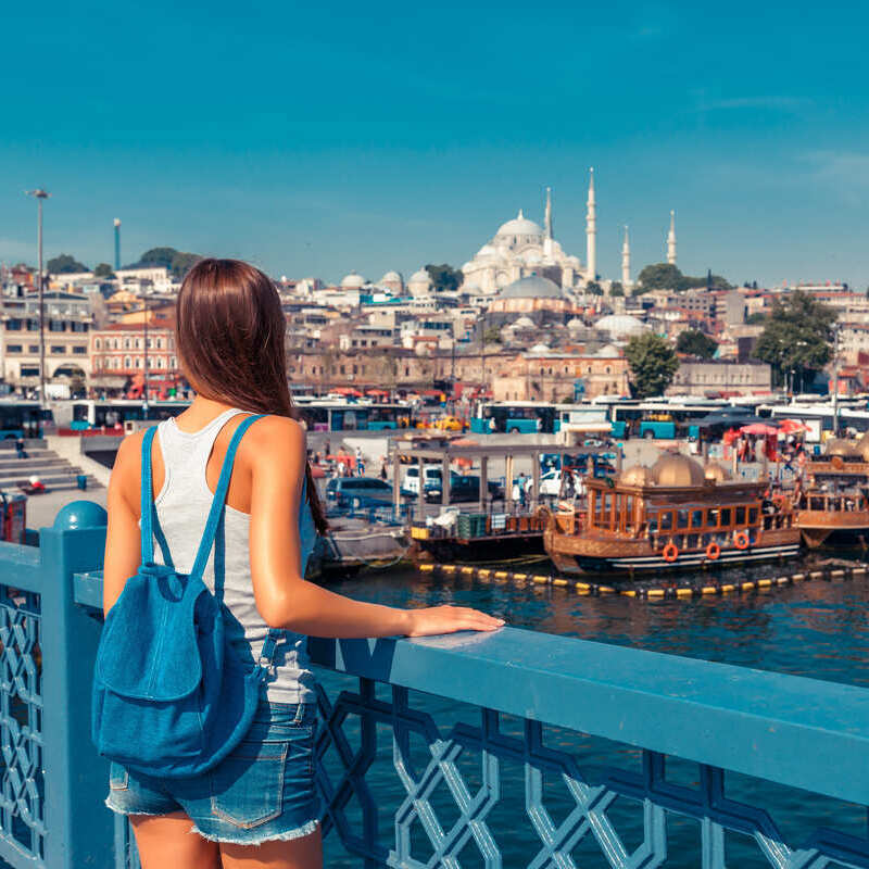 Ung kvinnlig turist avbildad med sin ryggsäck när hon står på Galatabron och tittar på den historiska halvön Istanbul, Turkiet, Turkiet, Eurasien, Mellanöstern, Östeuropa