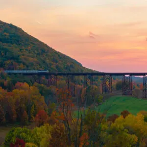 train on bridge with sunset and mountain