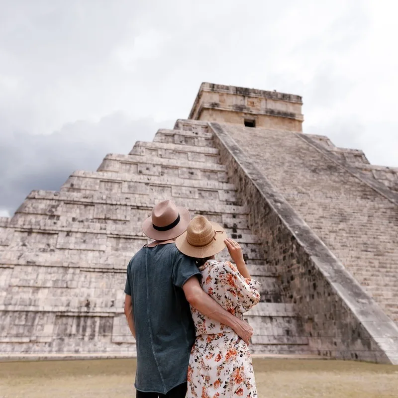 Una pareja joven mirando la pirámide maya de Chichén Itzá en la Península de Yucatán en México