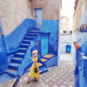 A Young Woman Wearing A Yellow Dress As She Walks The Blue City Of Chefchaouen, In Morocco, North Africa