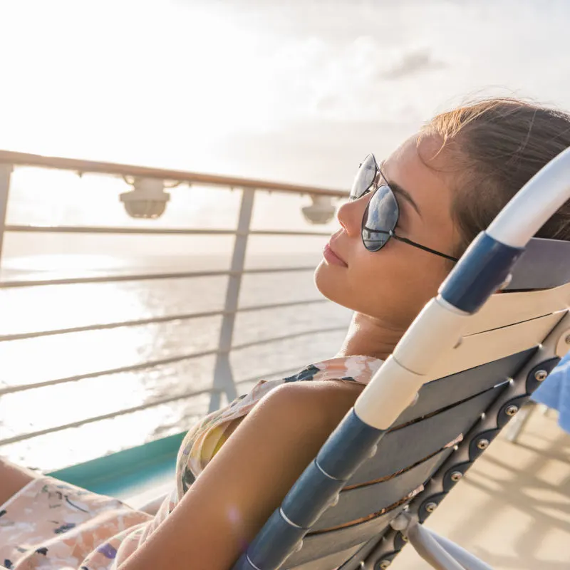 A cruise ship passenger lounges in the sun on a chair