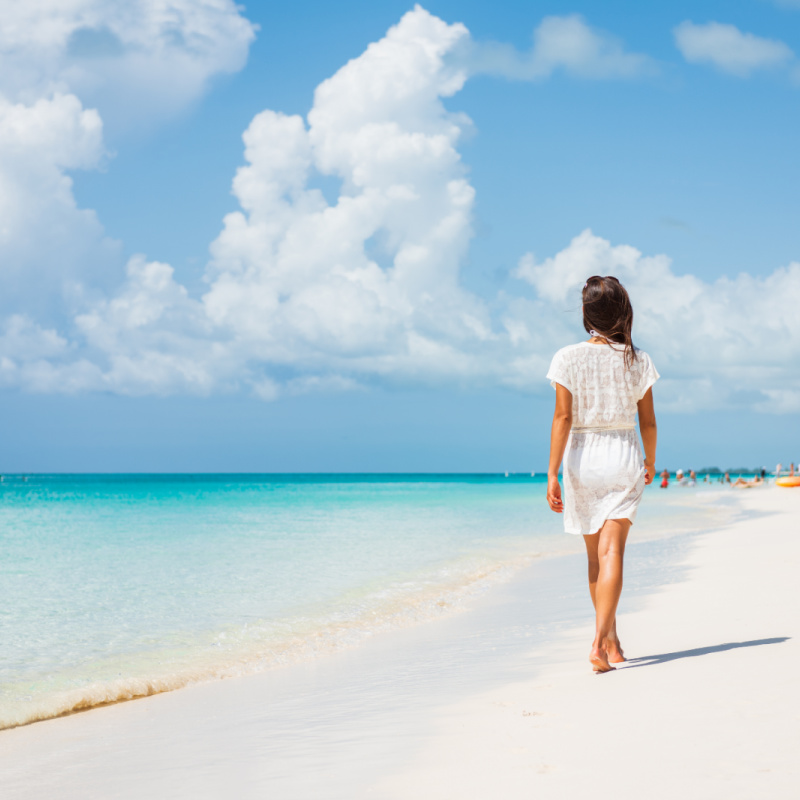 Kvinna som går längs stranden i Turks och Caicos