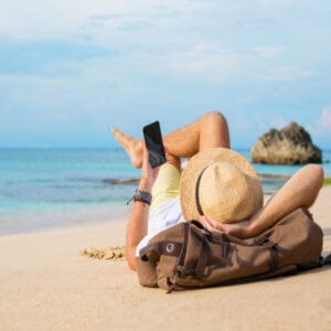 traveler looking at phone on beach