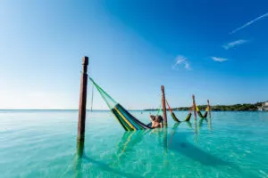 Handsome male tourist relaxing in a hammock in Laguna Bacalar in Mexico during kayak trip.