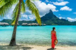 Bora Bora luxury hotel vacation tourist woman relaxing by ocean beach with view of Mt Otemanu in Tahiti, French Polynesia