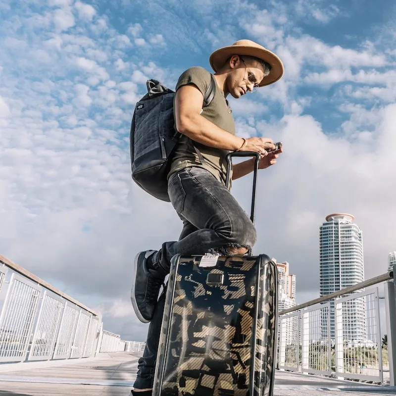 Travelers with hat and bags using his phone in Miami