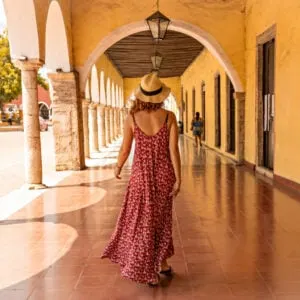 Young woman back view wearing hat walking throung the arch corridor in the historical part of Valladolid town, Mexico (1)