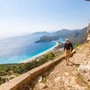 Tourist hikes the Lycian Way trail through the ancient sites of Antalya, Turkiye with Mediterannean sea views