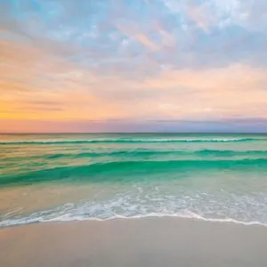 beach with green blue water and sunset in the background