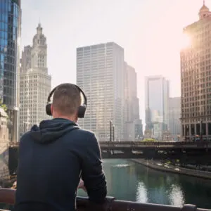 man with headphones looking at chicago river