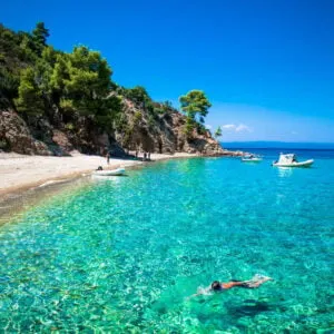A Tourist Swimming In A Turquoise Blue Mediterranean Sea Off The Coast Of Robinson Beach, Halkidiki Peninsula, Northern Greece