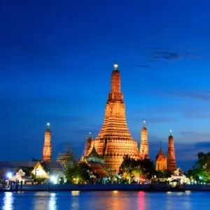 City with long triangle shaped building at night by the water
