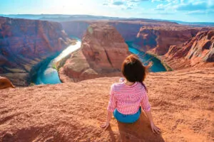Rear view of a young woman enjoying a view of the incredible Horseshoe Bend, the horseshoe meander of the Colorado River in Page, Arizona.