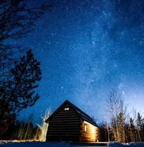 Starry night with a wooden cabin