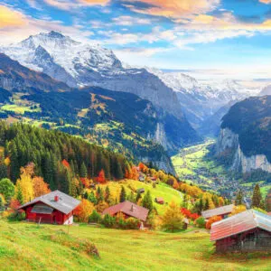 Swiss Cottages Amid A Verdant Autumnal Nature With Dramatic Snowy Peaks In The Background, Switzerland, Central Europe
