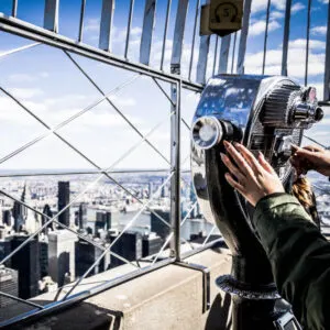 woman viewing new york city through binoculars