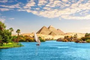 Boat Traveling Down The Nile With The Pyramids Of Giza For Background In Egypt, North Africa