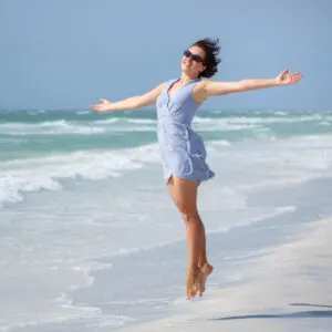 young woman jumping for joy on siesta key beach in sarasota florida