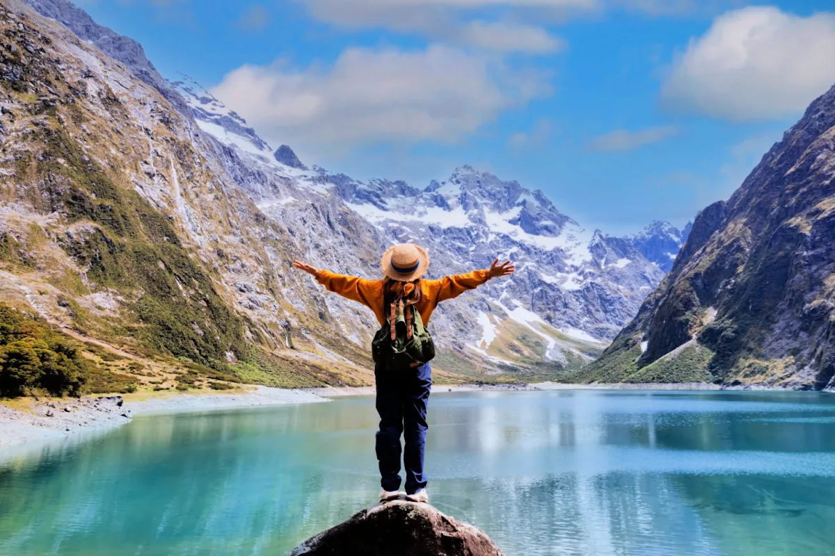 Happy young woman look on the mountain landscape. Travel and active life concept as Adventure travel in the mountains region in lake marian fiordland national park